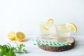 Two glasses of lemon homemade lemonade with mint leaves and ice on round wooden cut board on light background Royalty Free Stock Photo