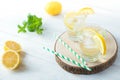 Two glasses of lemon homemade lemonade with mint leaves and ice on round wooden cut board on light background. Royalty Free Stock Photo