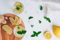 Two glasses with lemonade. Ingredients ginger, lemon, mint, ice on white surface. Wooden tray. Flat lay Royalty Free Stock Photo