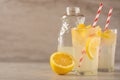 Two glasses of lemonade with lemons and lime and straw, a bottle with a cool drink and summer mood, with ice, freshness in hot