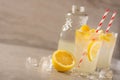 Two glasses of lemonade with lemons and lime and straw, a bottle with a cool drink and summer mood, with ice, freshness in hot