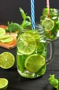 Two glasses of lemonade or mojito cocktail with fresh limes and mint.