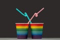 Two glasses of LGBT color with pink and blue cocktail tubes. Gray background. The concept of unification and love of people of a