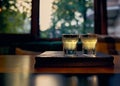 Two glasses of limoncello on a wooden stand against the backdrop of a blued window