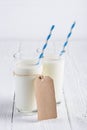 Two glasses of milk with blue stripped paper straw and blank paper tag