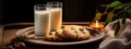 Two glasses of milk and chocolate chip cookies on a wooden tray, cozily lit by a candle and decorated with a green sprig Royalty Free Stock Photo