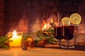 Two glasses with mulled wine, a candle, fir branches with decorations on a wooden table against the background of a Royalty Free Stock Photo