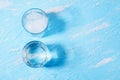 Two glasses, one glass full of ice, the other half with water on a blue background. The concept of ice melting Royalty Free Stock Photo