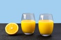Two glasses with orange juice, half of orange fruit next to glass as drink,