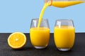 Two glasses of orange juice, juice being poured into a glass, half of the fruit next to the glass with drink, healthy eating Royalty Free Stock Photo