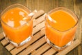 two glasses with orange juice with straws on a wooden support/two glasses with orange juice with straws on a wooden support. Top