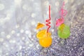 Two glasses with orange and lime juice, decorated with cocktail umbrellas and ice tubes, as well as citrus slices on a gray Royalty Free Stock Photo