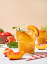 Two glasses with peach tea with ice and mint close up. Vegetarian and healthy homemade cold drink on a light background with fresh Royalty Free Stock Photo