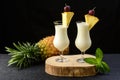 Two glasses with pina colada cocktail, a whole pineapple next to the drinks, Royalty Free Stock Photo