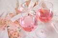Two glasses with pink grape wine with flowers and gift box on the background. Romantic dinner concept
