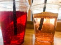 Two glasses of plastic red and yellow refreshing cold tasty sweet raspberry strawberry cherry orange peach lemon fruit lemonade Royalty Free Stock Photo