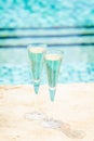 Two glasses of prosecco at the edge of a resort pool. Concept