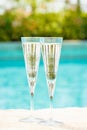 Two glasses of prosecco at the edge of a resort pool. Concept
