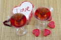 Two glasses with a red alcoholic drink and heart shaped candles Royalty Free Stock Photo