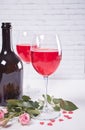 Two glasses with red grape wine with bottle and roses on the background. Romantic dinner concept Royalty Free Stock Photo