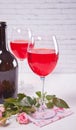 Two glasses with red grape wine with bottle and roses on the background. Romantic dinner concept Royalty Free Stock Photo