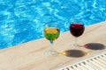 Two glasses of red and white wine are placed by the pool. The concept of a pleasant stay. Royalty Free Stock Photo