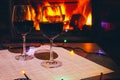 Two glasses of red wine against the background of a burning fireplace in hard reflective lighting. Romantic relaxed dinner by the