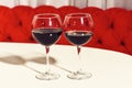 Two glasses of red wine, alcoholic drink, beverage, served on white table in cafe or bar on sofa background. Royalty Free Stock Photo
