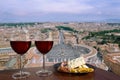 Two glasses of red wine with assortment of cheese and meat against view of Saint Peter`s Square in Vatican, Rome, Italy. Rome