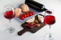 Two glasses of red wine, a bottle of red wine, cheese on a wooden chopping Board, pears, grapes, walnuts, cherry tomatoes. Bread Royalty Free Stock Photo