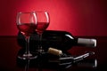 Two glasses of red wine, bottle and crokcrew on red and black background Royalty Free Stock Photo