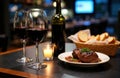 Two glasses of red wine, a bottle of wine, and a plate of steak with bread on a Royalty Free Stock Photo