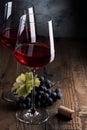 Two glasses of red wine and a bunch of grapes on an old wooden table Royalty Free Stock Photo