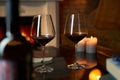 Two glasses of red wine and candle on table at home, fireplace in the background. Royalty Free Stock Photo