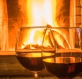 Two Glasses of red wine before fireplace.