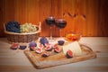 Two glasses of red wine, figs, cheese, bunches of grape and bowl of honey on wooden table. Royalty Free Stock Photo