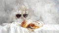 Two glasses of red wine, two loaves of bread, and a white linen cloth on a rustic backdrop Royalty Free Stock Photo