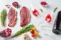 Two glasses of red wine near bottle and beef steaks over white concrete background, side view Royalty Free Stock Photo