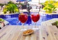 Two glasses with red wine Sangria on the table against the backdrop of the pool. Royalty Free Stock Photo