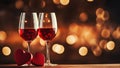 Two glasses of red wine standing on table with heart shape on festive golden bokeh background. Love anniversary birthday Royalty Free Stock Photo