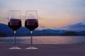 Two glasses of red wine with view of sunset over lake and mountains Royalty Free Stock Photo