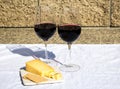 2 glasses of wine with cheddar cheese, and crackers on an outdoor table
