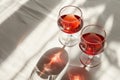 Two glasses of red wine on white tabletop. Direct sunlight from the window with strong shadows. Top view, copy space Royalty Free Stock Photo