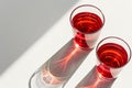 Two glasses of red wine on white tabletop. Direct sunlight from the window with strong shadows. Top view, copy space Royalty Free Stock Photo