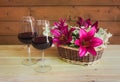 Two glasses of red wine and wicker basket with purple lilies and white hydrangea flowers. Selective focus Royalty Free Stock Photo