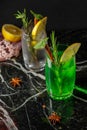 Two glasses with refreshing lemonade, a cocktail with lemon slices, mint and rosemary sprigs. On a black marble stand Royalty Free Stock Photo
