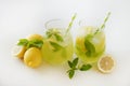 Two glasses of refreshing non alcoholic mojito drink with lemon slices, mint leaves and ice. Studio shot of iced lemonade isolated Royalty Free Stock Photo