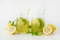 Two glasses of refreshing non alcoholic mojito drink with lemon slices, mint leaves and ice. Studio shot of iced lemonade isolated Royalty Free Stock Photo