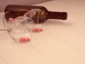 Two glasses with the remains and a bottle of wine lie on a white wooden background, a copy of the space Royalty Free Stock Photo