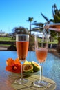 Two glasses of rose bubbles champagne or cava wine served outside on paradise island with palms and green grass